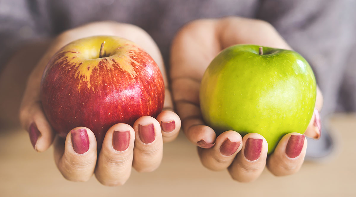 Vergleichsportale und deren Algorithmen: Eine Frau hält einen roten und einen grünen Apfel in der Hand 