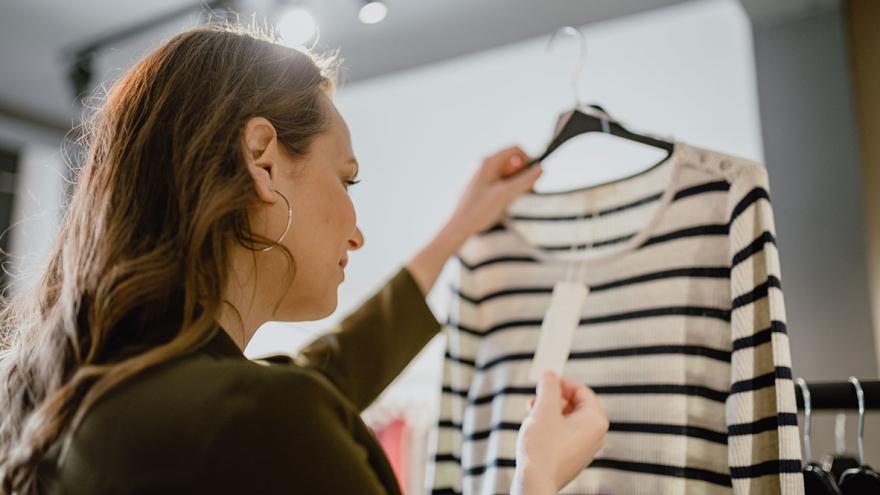 Dynamische Preisgestaltung: Eine Frau hält einen Pullover hoch und betrachtet das Preisschild 