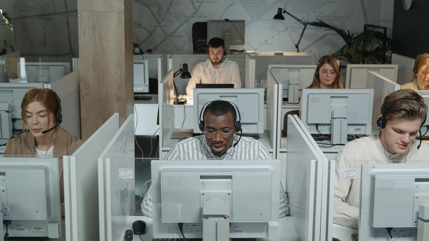 Mitarbeiter eines Callcenters sitzen an ihren Arbeitsplätzen