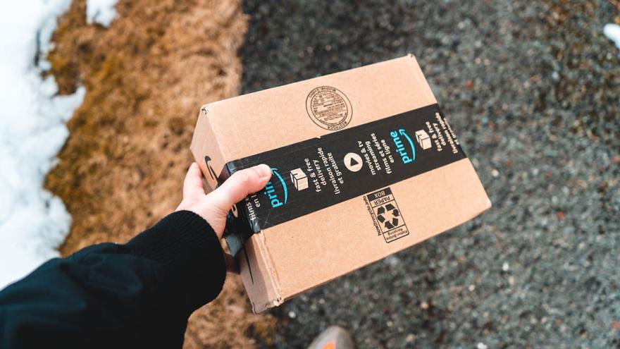 Ein Paketbote trägt ein Paket des Versandhändlers Amazon