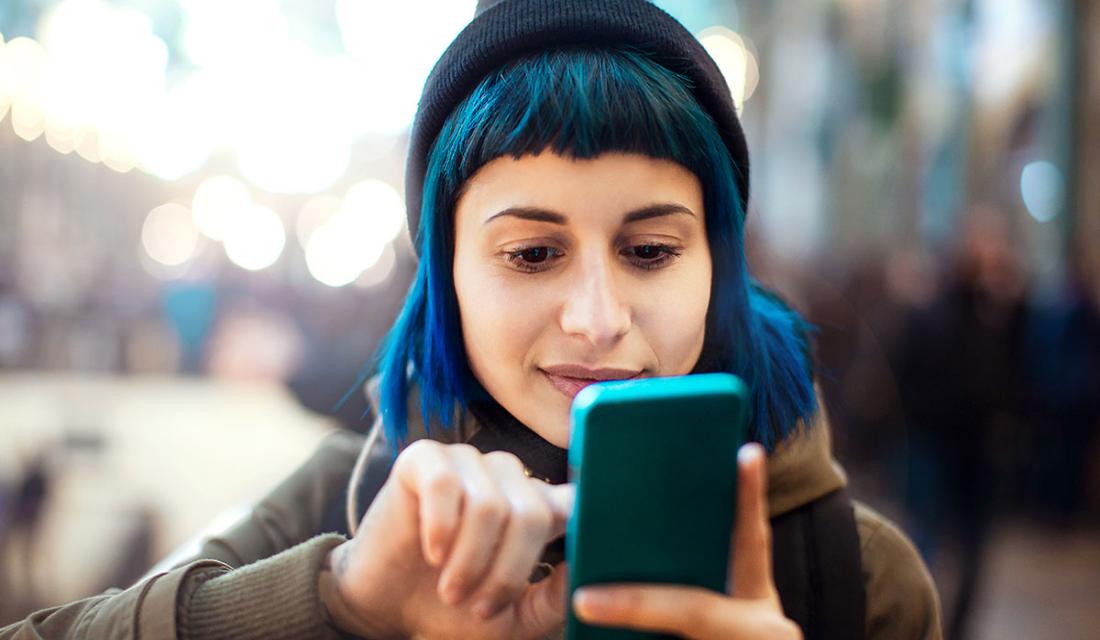 Eine junge Frau mit blauen Haaren macht ein Selfie von sich